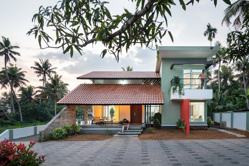 Street view of the residence with terracotta tile roofs and palm trees under an overcast sky