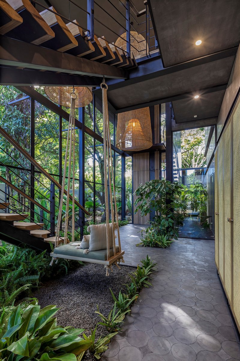 Interior courtyard with slate paving, hanging swing seat, and floor-to-ceiling glazing filtering daylight
