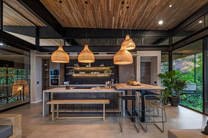 Open kitchen with concrete island and woven pendant lights beneath a slatted timber ceiling