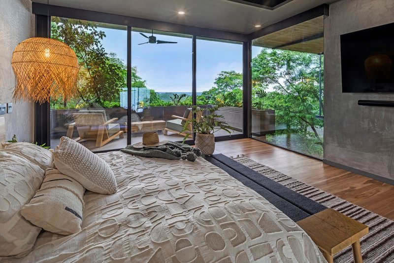 Bedroom with floor-to-ceiling glazing overlooking a terrace and tree canopy