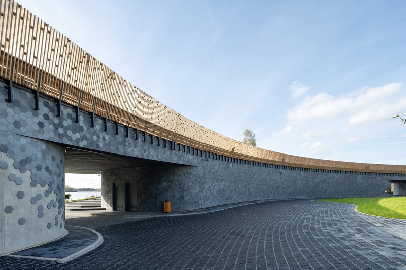 Curved paved courtyard beneath timber louvered roof canopy with view through to waterfront