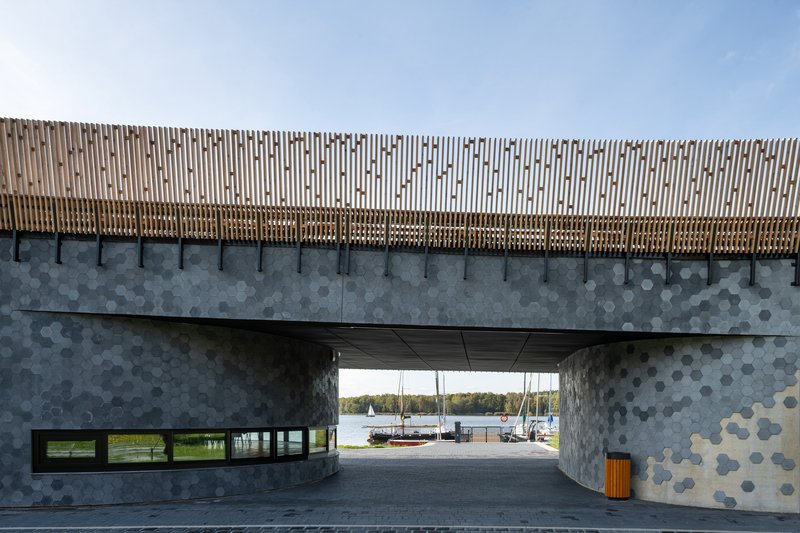 Portal view through hexagonal tiled concrete walls framing sailboats at the marina beyond