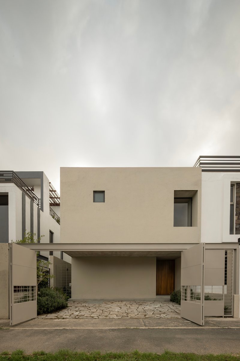 Street facade with recessed carport and cantilevered upper volume in smooth stucco under overcast sky