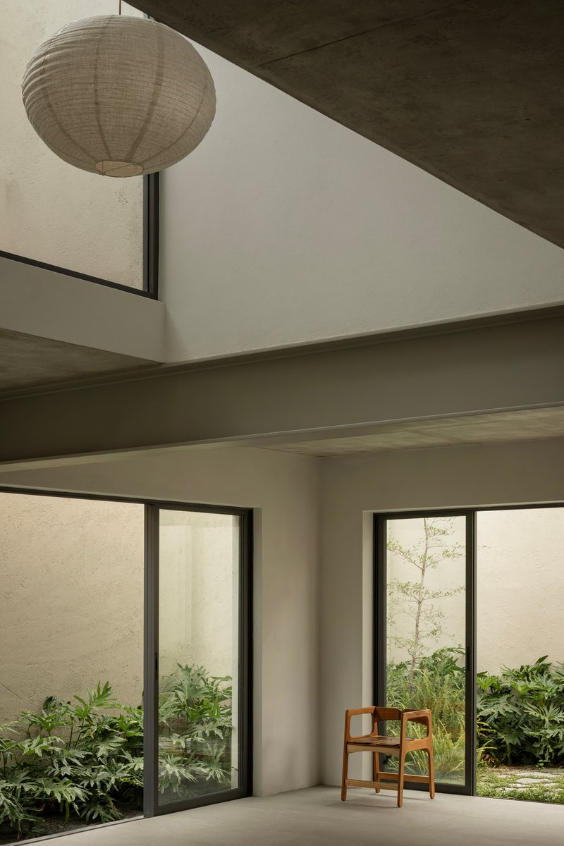Double-height interior space with paper lantern and glazed doors opening to planted courtyards
