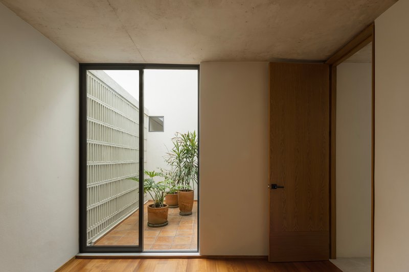 Interior room with timber door opening to tiled terrace and glass block wall