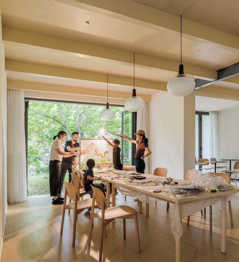 Reading room with timber table and pendant lights where a group gathers for an art workshop
