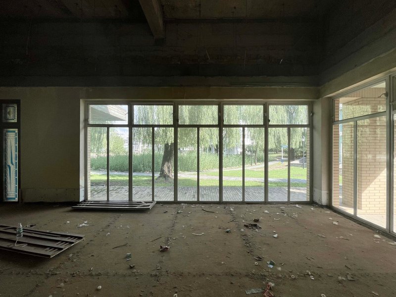 Unfinished room with floor-to-ceiling glazing overlooking willow trees and a paved courtyard