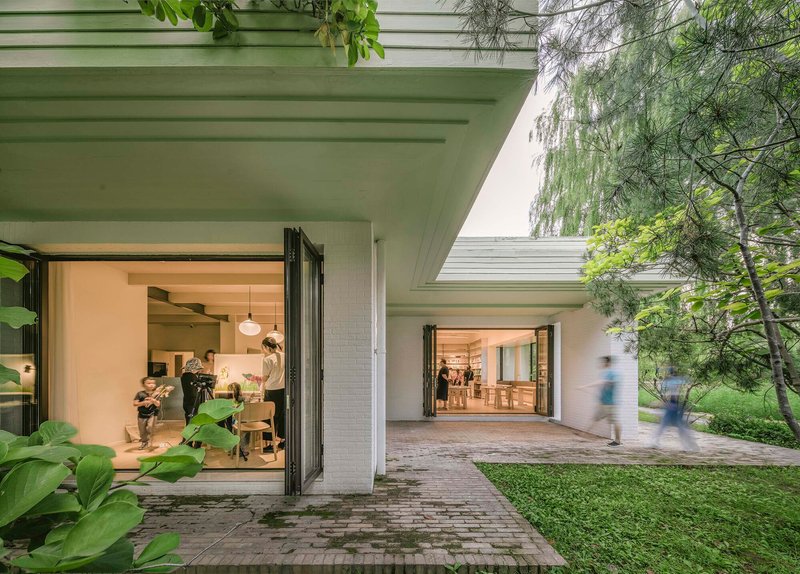 Covered walkway with exposed concrete ceiling beams and open folding doors leading to interior rooms