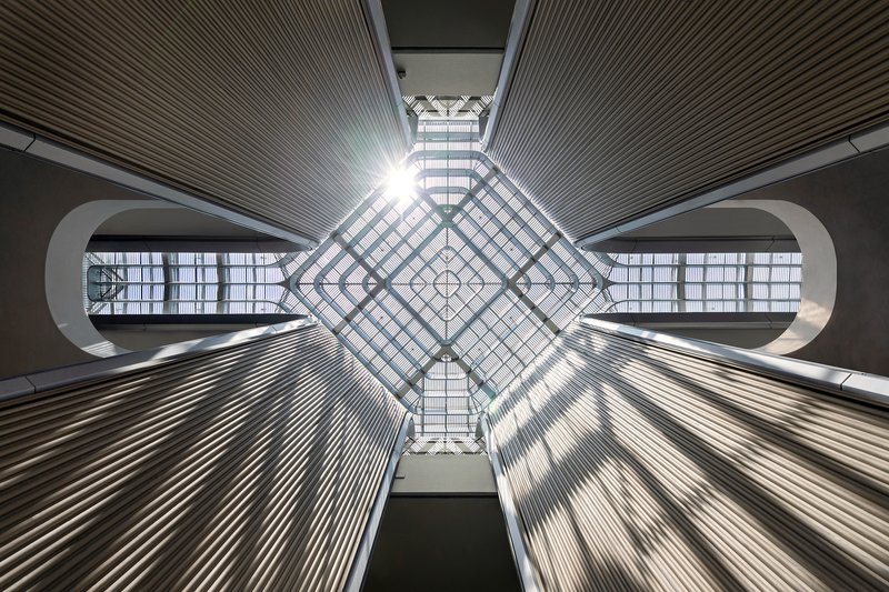 View directly upward into the diamond-grid skylight with radiating ribbed ceiling panels and bridge openings