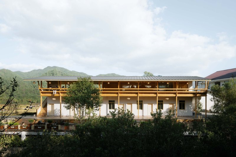 Three-story facade with exposed timber frame and deep overhanging eaves set against forested mountains