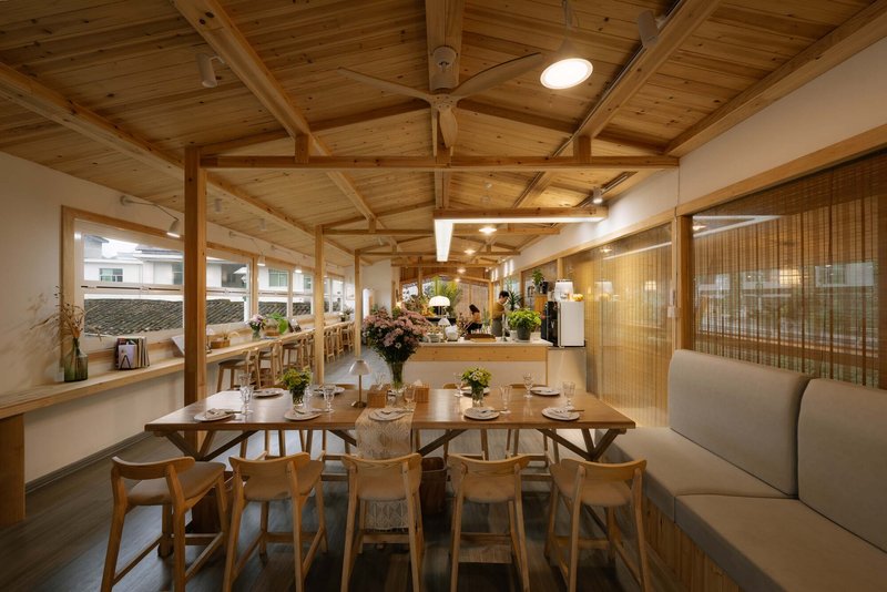 Dining area with exposed timber frame ceiling and bamboo screen partitions under warm lighting
