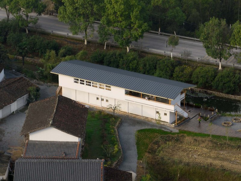Aerial view showing the corrugated metal roof and clerestory windows adjacent to a tree-lined road