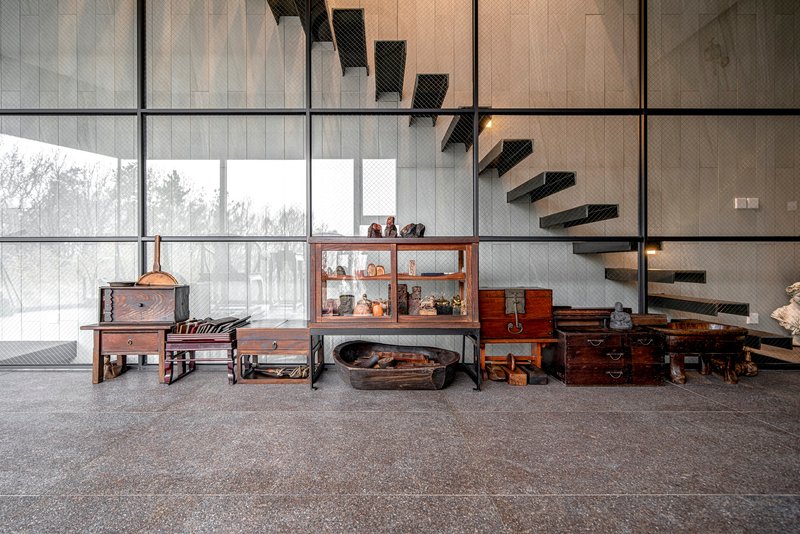 Floating black steel staircase alongside floor-to-ceiling gridded windows framing bare winter trees