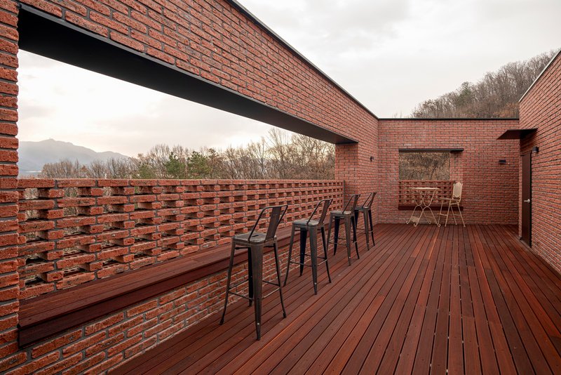 Rooftop terrace with perforated brick parapet wall and timber decking under an overcast sky