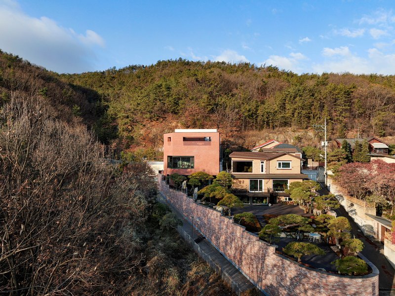 Aerial view of the red brick structure set into a hillside with terraced garden and retaining walls