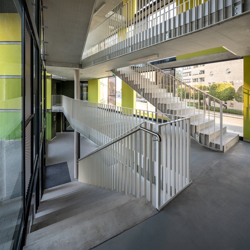 Interior view of the multi-level concrete staircase with vertical metal balustrades under a coffered ceiling