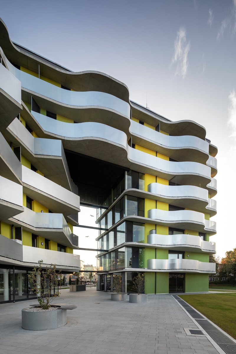 Courtyard view of the undulating white balconies and exposed diagonal bracing with planted beds below