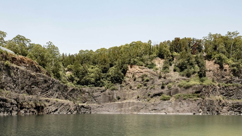 View across a quarry lake showing the vegetated rock walls and distant forested ridges