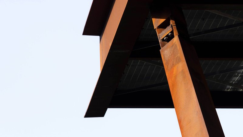 Looking up at the weathered steel frame connection with diagonal timber deck boards above