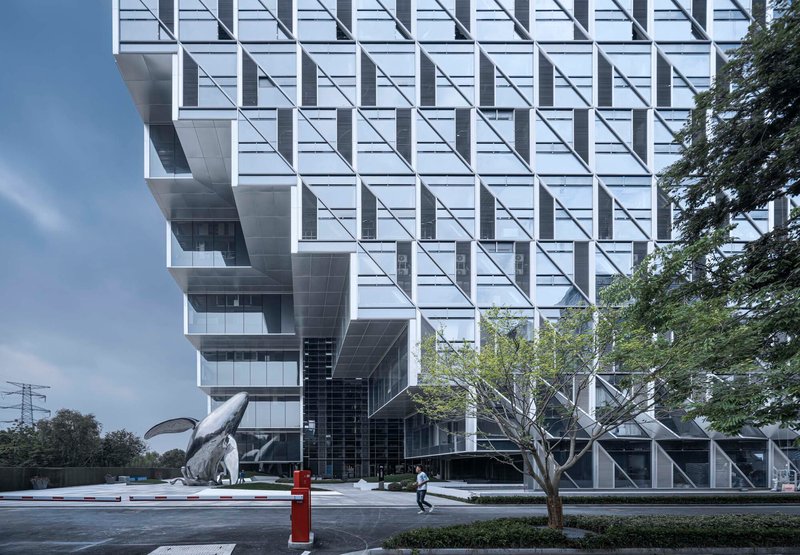 Street view of the white paneled facade with diagonal bracing patterns and a pedestrian crossing below