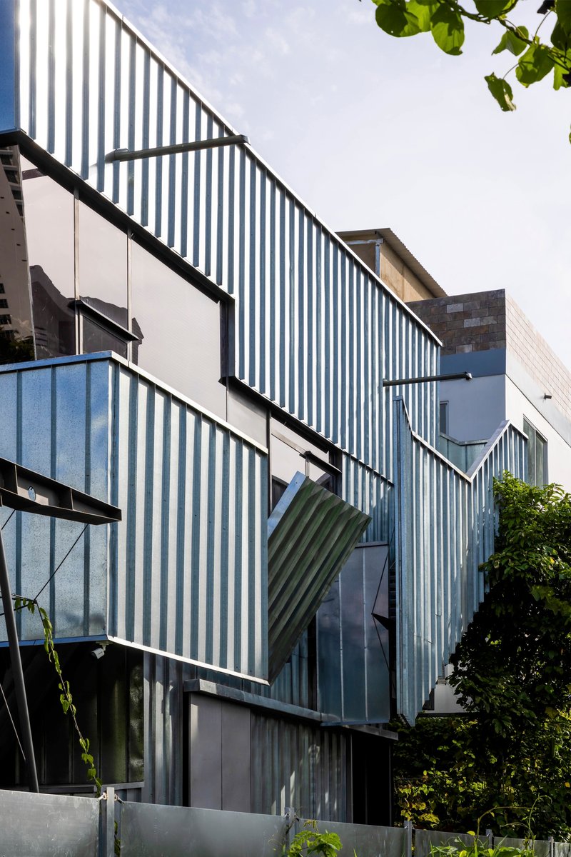 Detail of the articulated corrugated metal facade with angled panels and integrated window openings