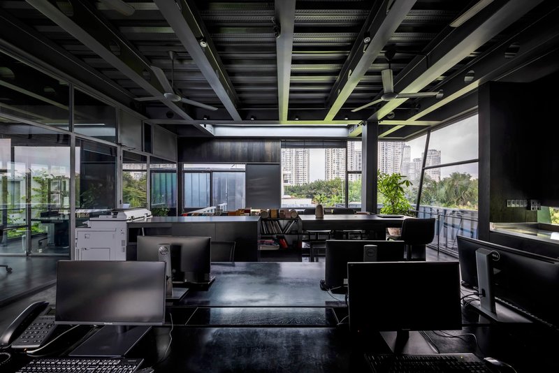 Office workspace with exposed steel ceiling structure and workstations arranged below continuous skylights
