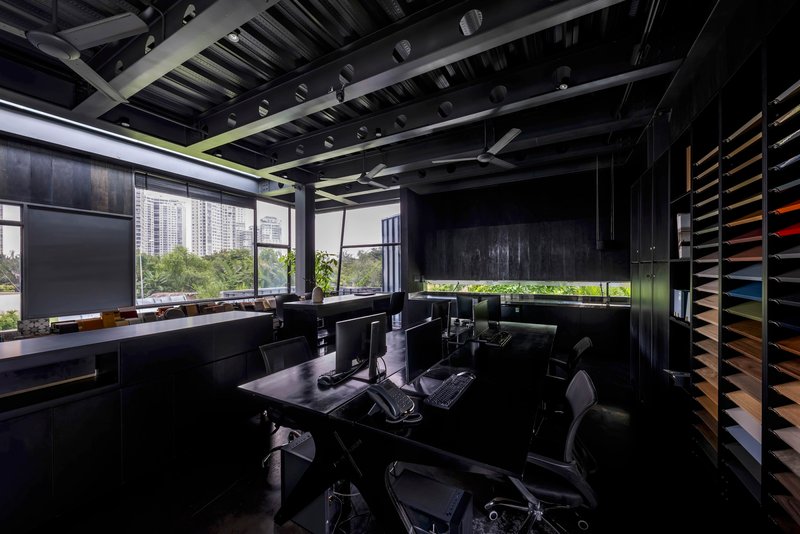Interior office view showing horizontal window slot framing vegetation and distant towers under exposed rafters