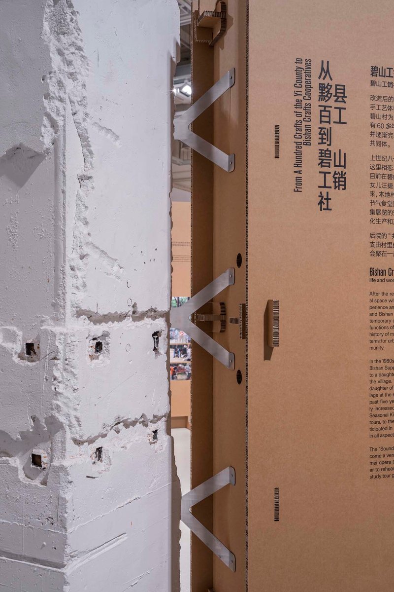 Detail of cardboard stairs and exhibition panels alongside a weathered white column