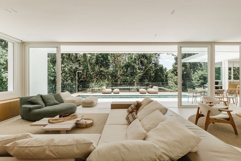 Living room with floor-to-ceiling glass walls overlooking a swimming pool and garden courtyard
