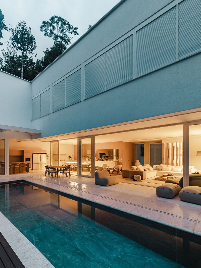 Rear facade at twilight showing two-story volume above the pool terrace and outdoor seating