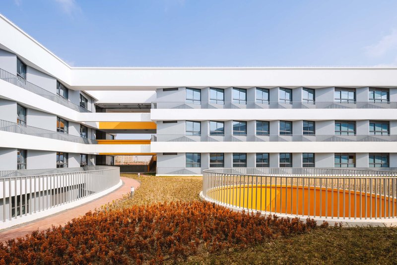Courtyard view showing planted beds with orange and brown foliage against yellow vertical railings