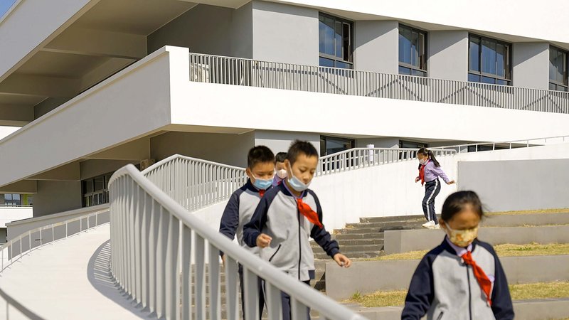 Students with backpacks descending curved outdoor stairs with white metal railings in afternoon light