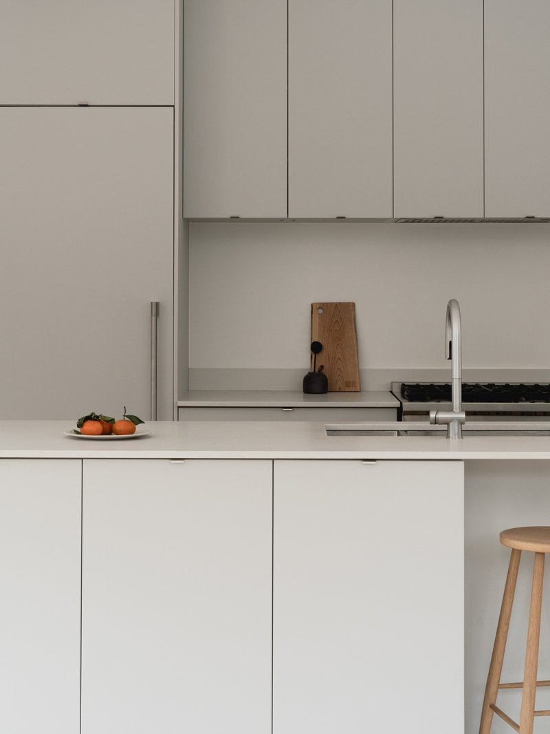 Kitchen counter with pale grey cabinetry, open shelving, and two persimmons beside the sink