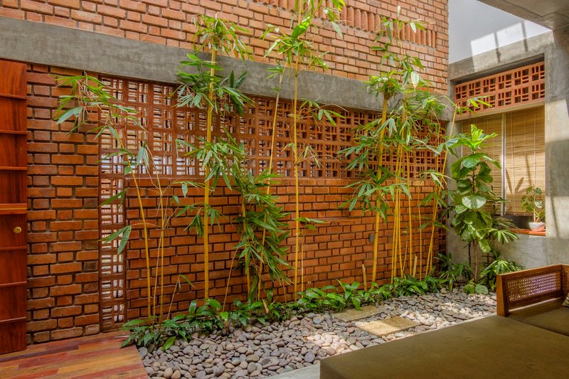 Interior courtyard with bamboo planted in a gravel bed beneath latticed brick screens and exposed concrete beams