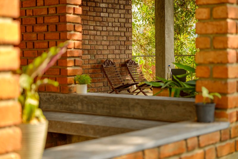 Split-level terrace with concrete steps, two folding chairs against brick wall, and bamboo screen framing the view