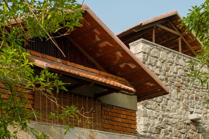 Upward view of timber-framed gabled roof with exposed rafters above painted stone and brick walls