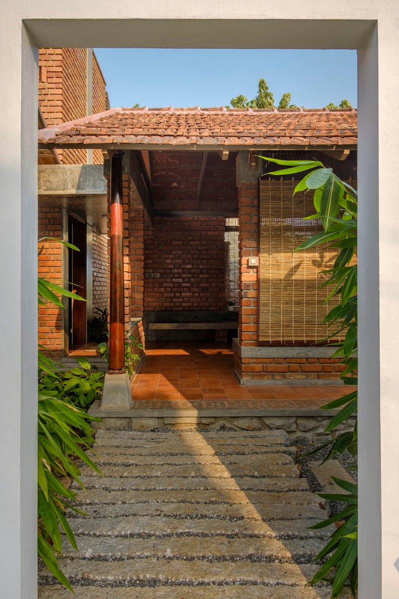 View through doorway to covered terrace with clay tile floor and bamboo screen in afternoon light