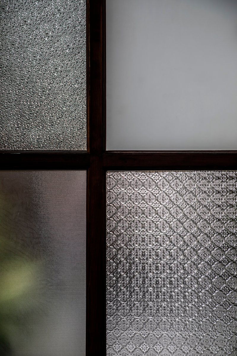 Four panes of textured and frosted glass in dark metal mullions filtering diffused daylight