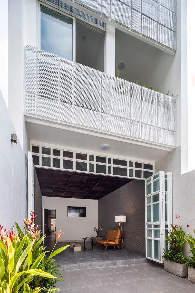 Open bi-fold glass doors leading into a sitting area flanked by potted tropical plants