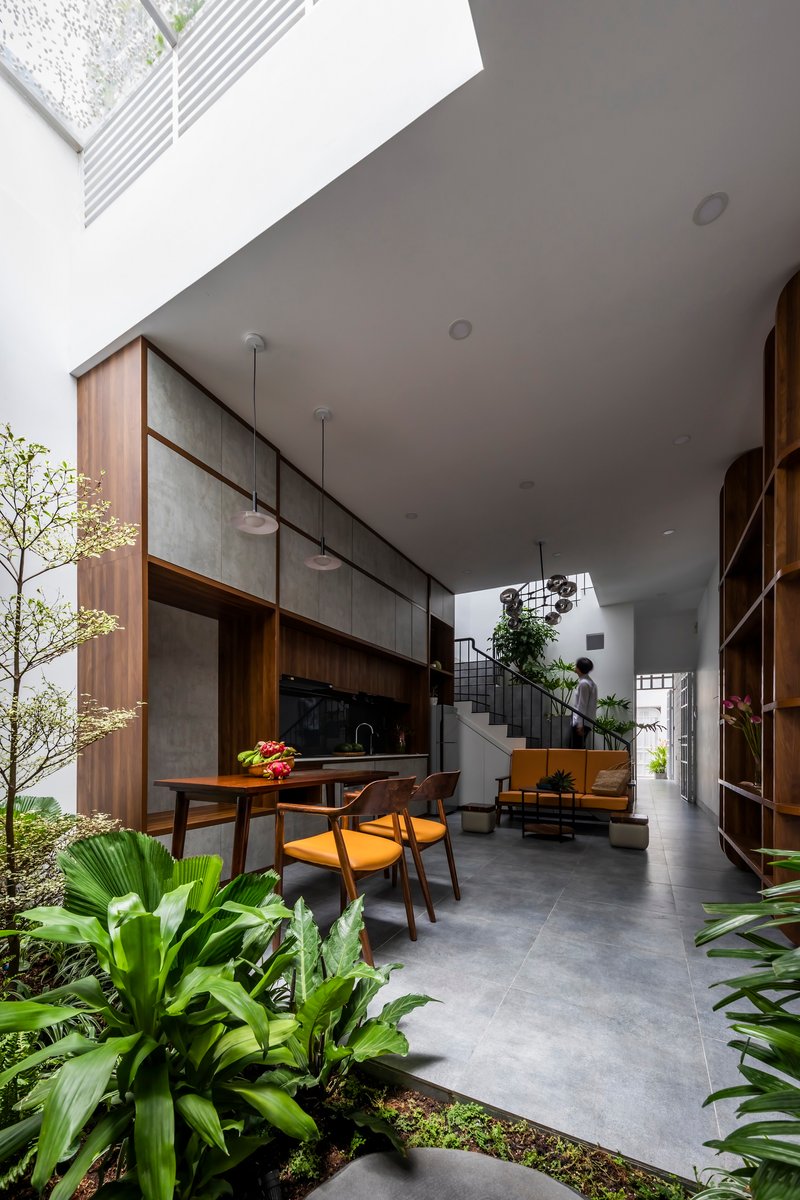 Living and dining area with timber cabinetry opening to an interior planted courtyard under a skylight