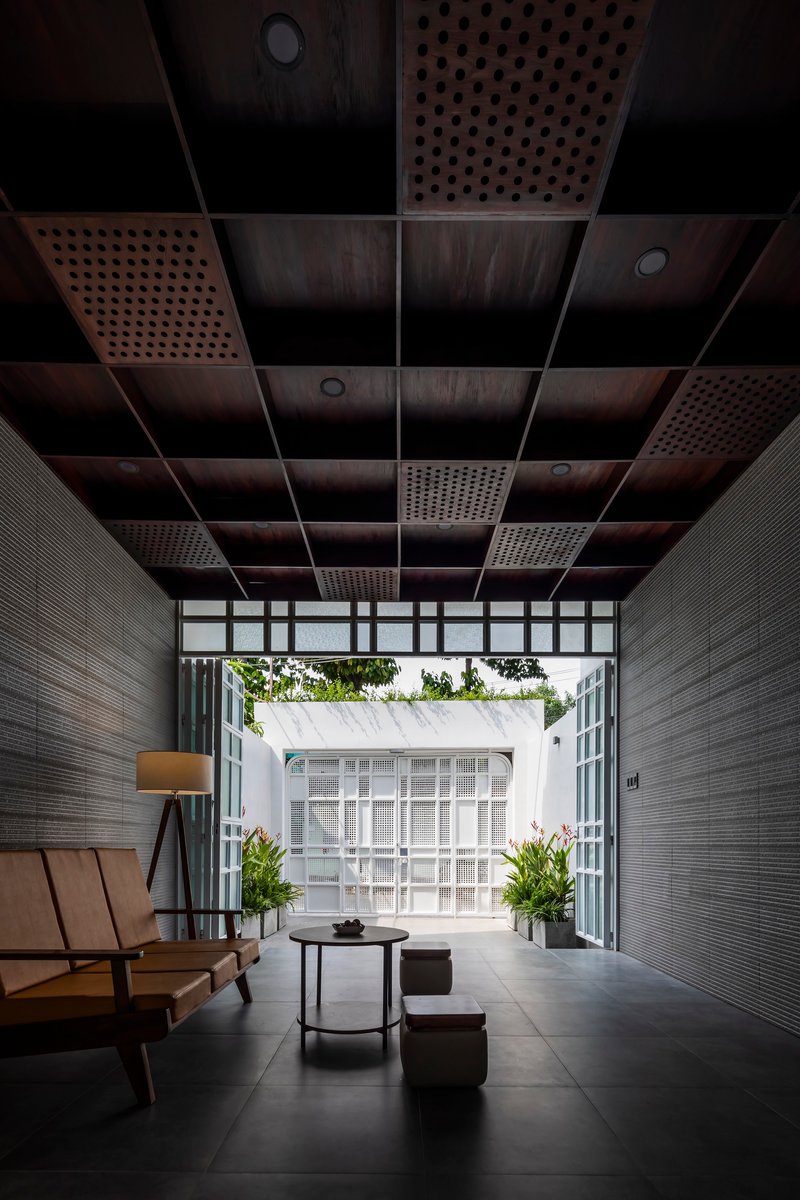 View through perforated ceiling panels toward the white perforated facade framed by textured wall tiles