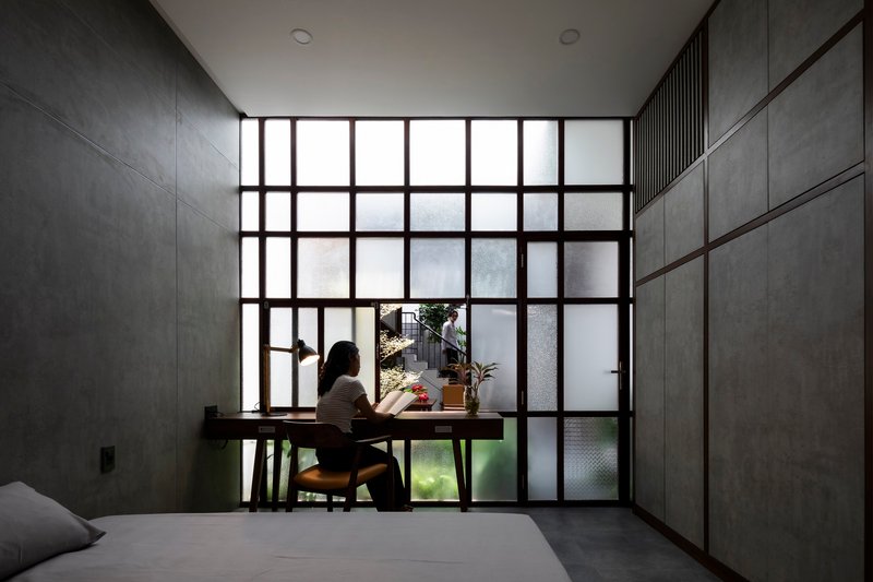 Person seated at a desk before a large gridded window overlooking an interior courtyard