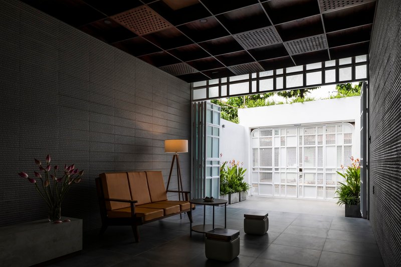 Interior lounge with dark textured walls and a view to the white courtyard facade through open doors