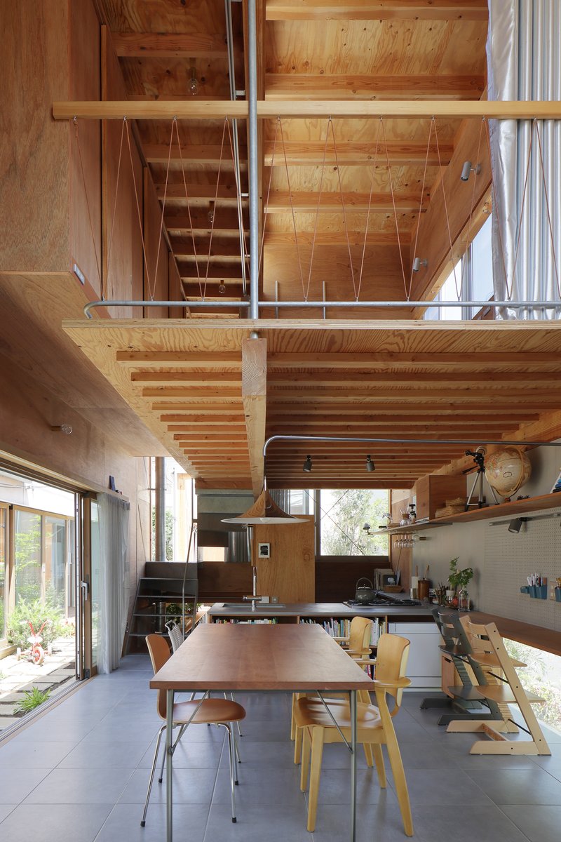 Double-height dining space beneath an exposed timber mezzanine and open stair structure