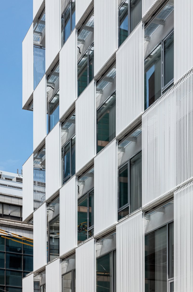 Diagonal view of the ribbed white cladding framing recessed balconies and glazed openings