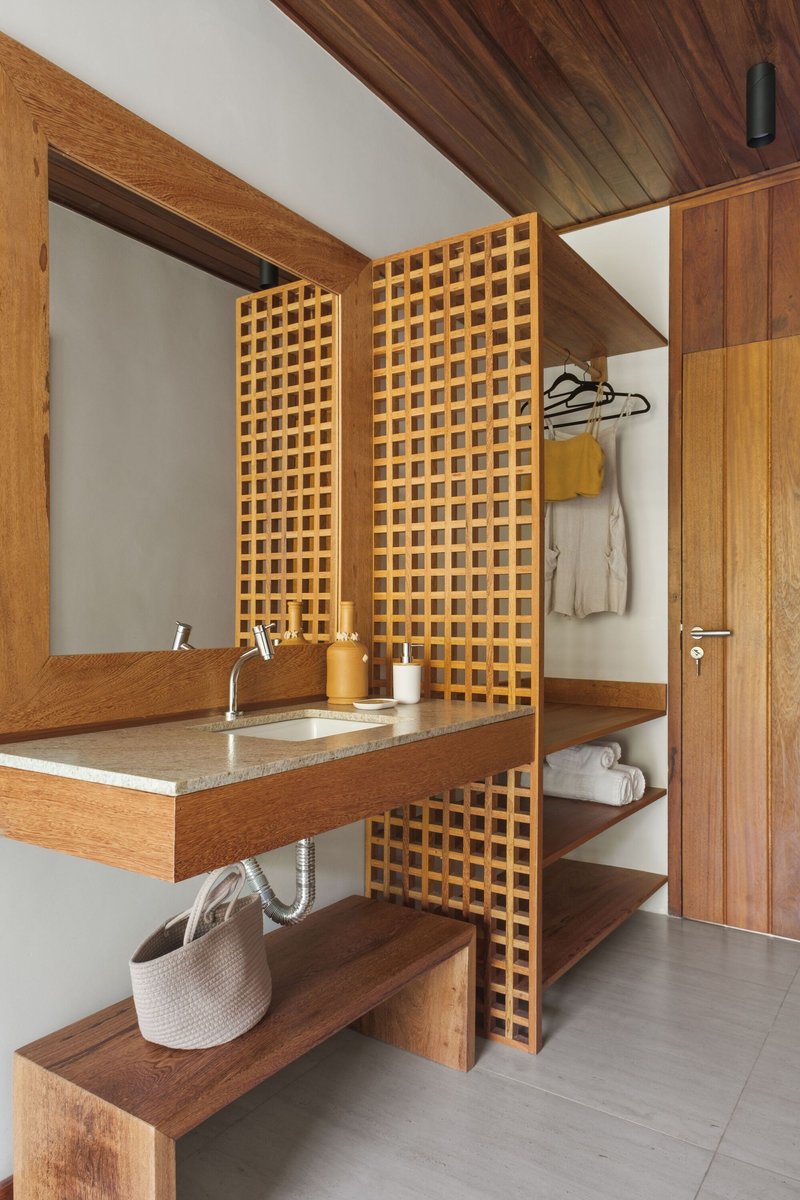 Bathroom vanity flanked by lattice timber screens with integrated shelving and a sloped ceiling panel