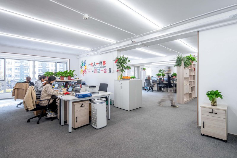 Open plan office with exposed ceiling beams and potted plants between workstations