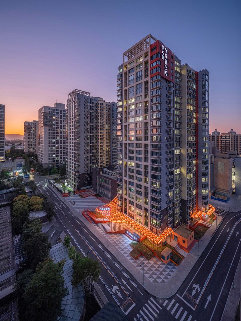 Elevated corner view of residential tower with orange canopy at base at dusk
