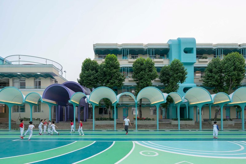 Row of arched canopies in pastel blue and purple shades sheltering a playground with children playing