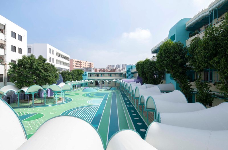 View across the painted playground surface toward rows of white and purple shell-like canopies under cloudy skies